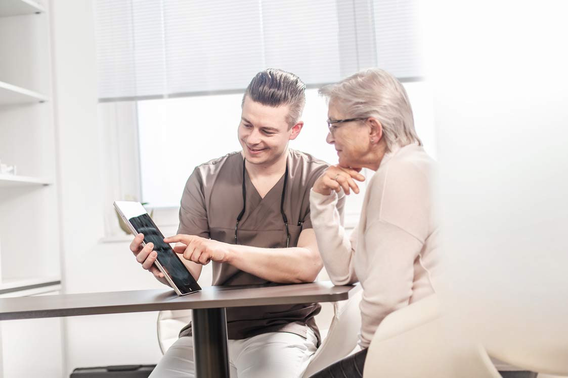 Dr. Müller berät eine Patientin anhand eines Tablets