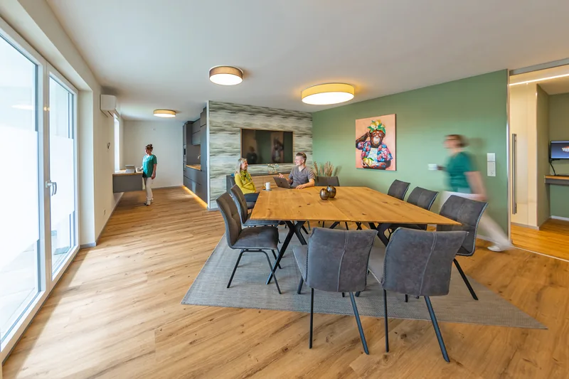 Großer Holztisch und Glasfront im früheren Lounge-Bereich, der heutigen Labor Lounge